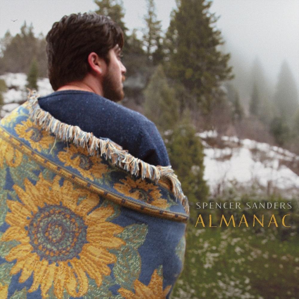 Almanac, album by Spencer Sanders. Sanders faces a meadow, wrapped in a woven blanket with a sunflower on it.