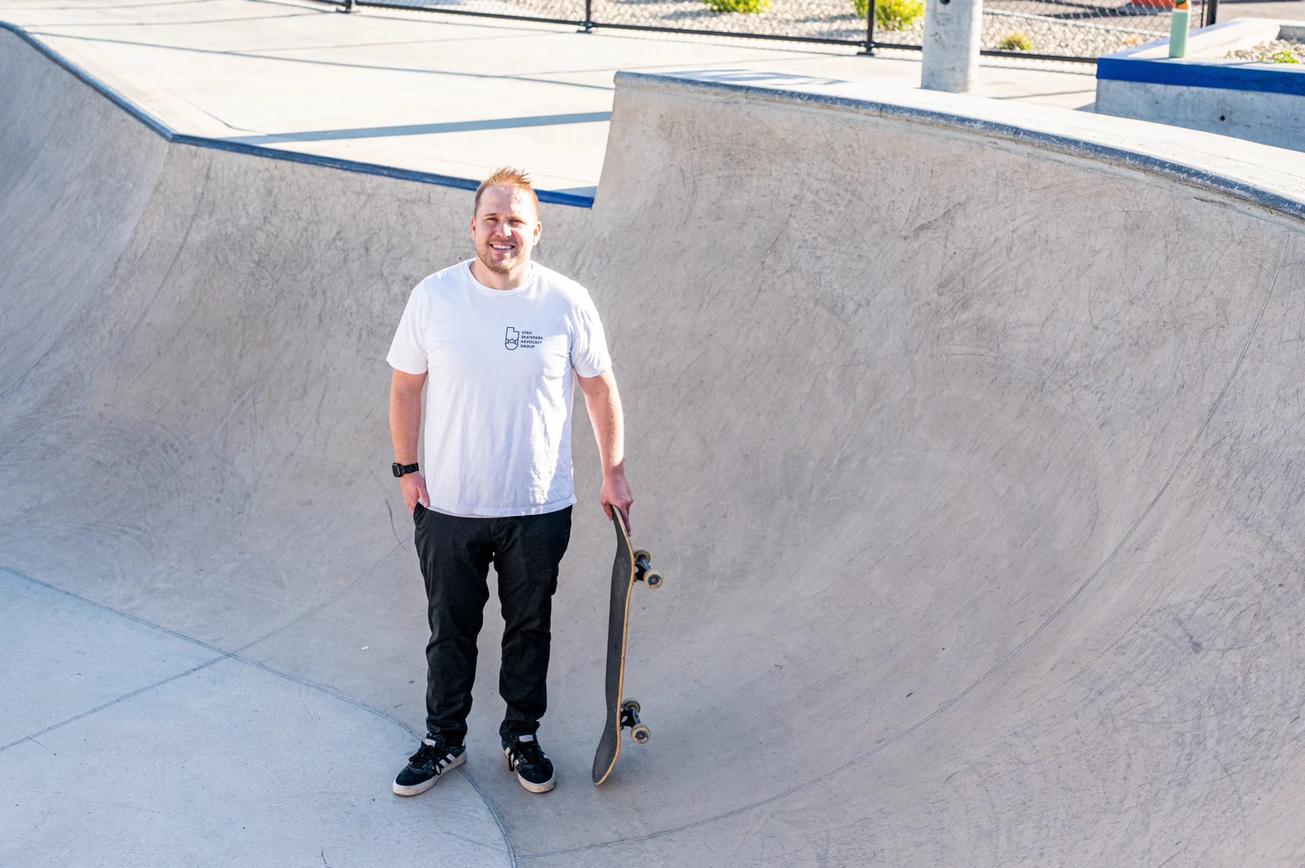 Utah Skatepark Advocacy Group founder Sean Peterson stands in a bowl at a skatepark at Cook Family Park in Pleasant Grove, Utah, with his skateboard.