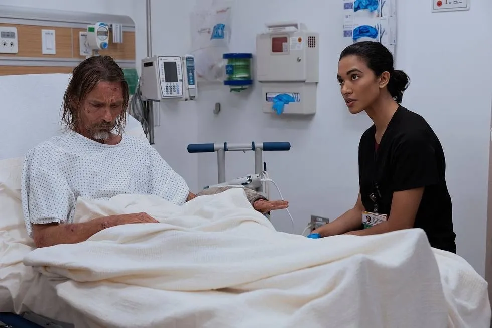 A man sitting in a hospital bed with a nurse.