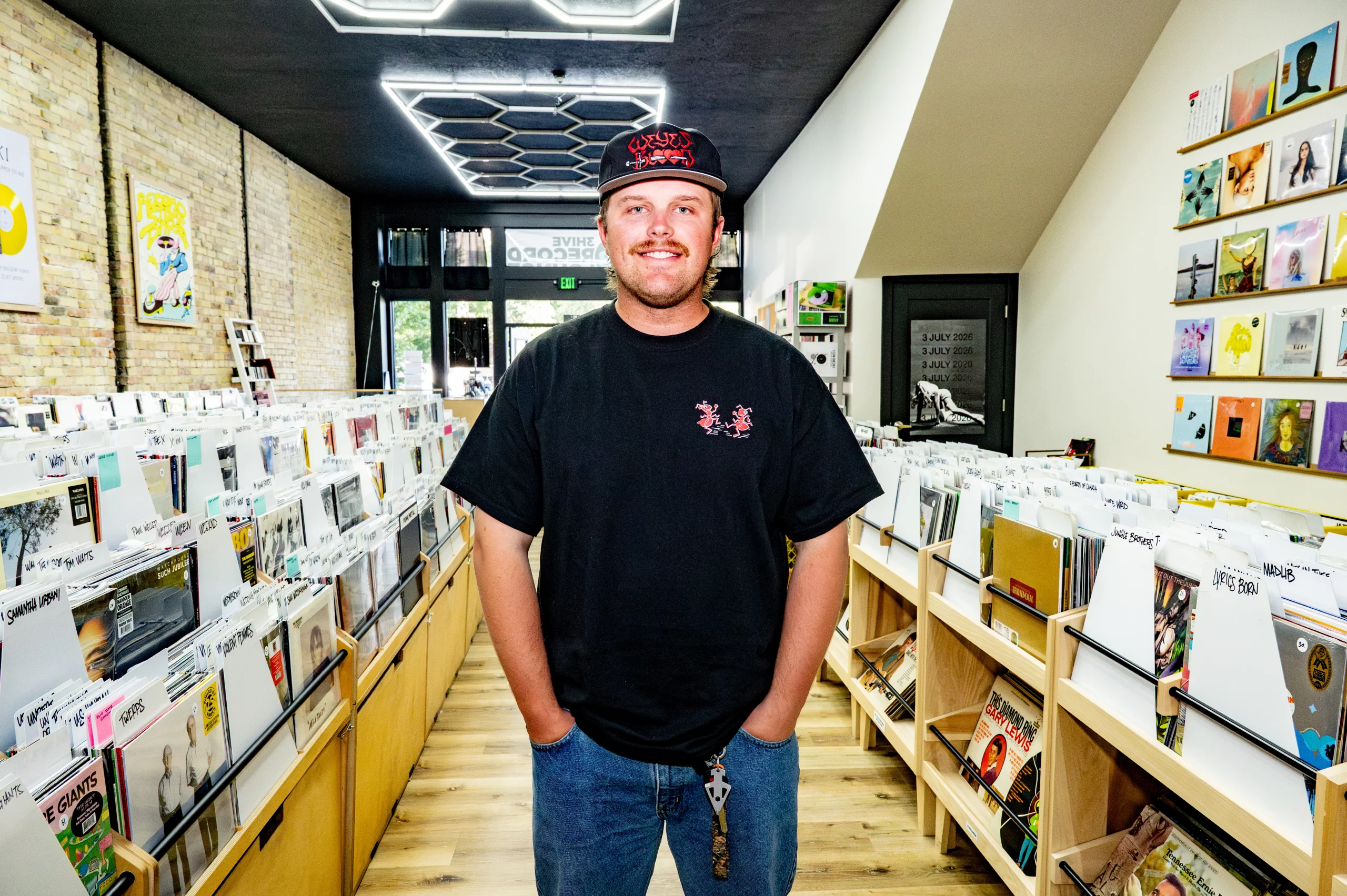 Jake Clements of Honeybee Reviews posing in between the isles of 3Hive Record Lounge