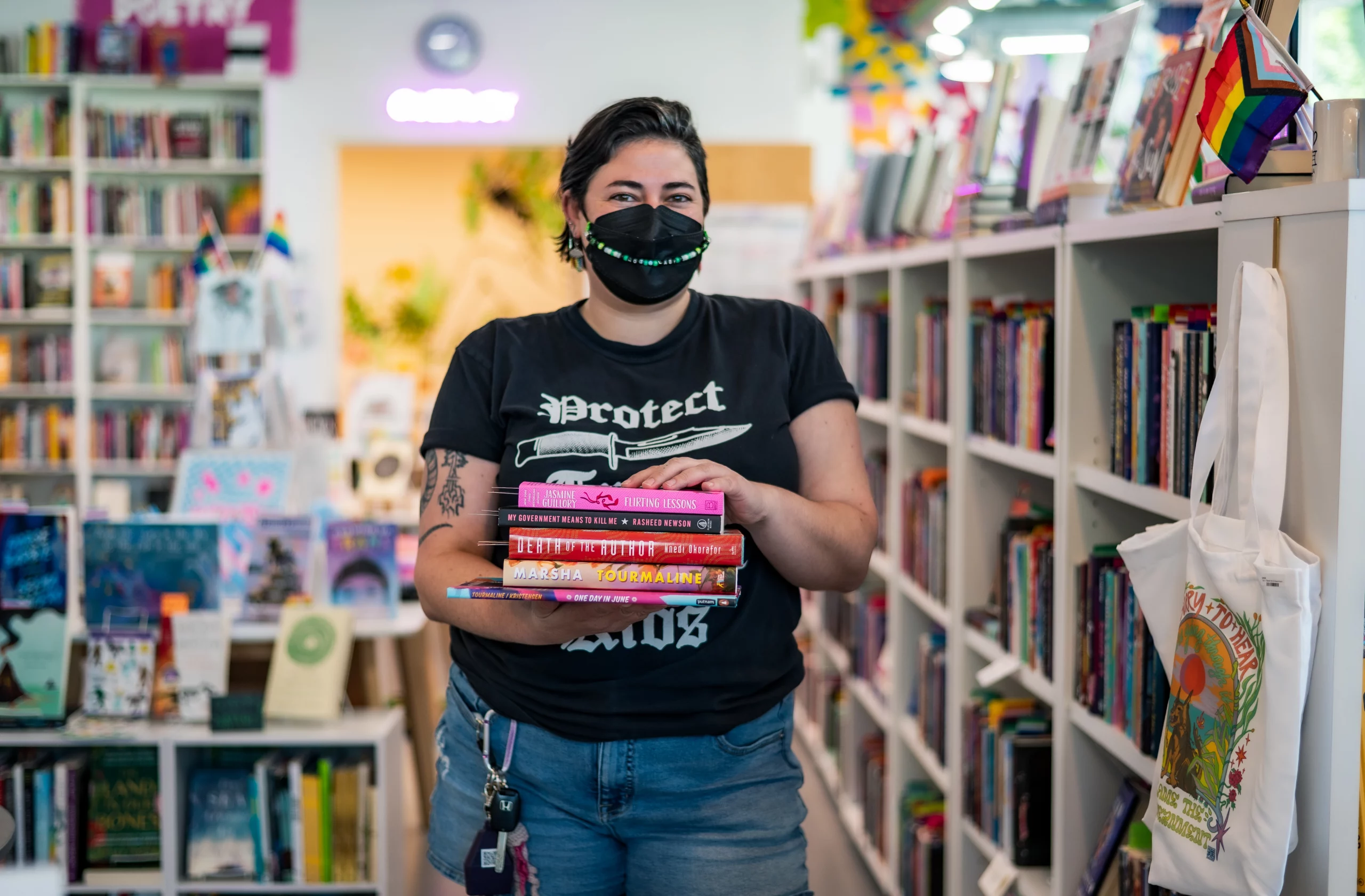 Under the Umbrella bookstore owner Kaitlyn Mahoney holding four of their favorite books inside the store.